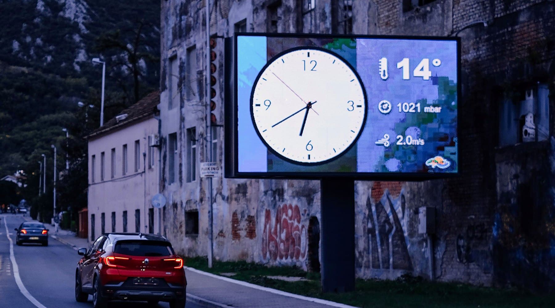 Painel de LED à beira de uma via urbana exibindo informações de hora e temperatura